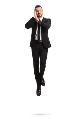 Beyaz arka planda uyuyan ve havada süzülen takım elbiseli bir iş adamı.