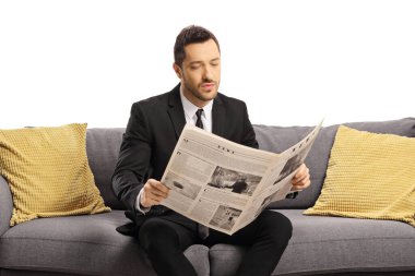 Kanepede oturan ve beyaz arka planda izole edilmiş bir gazete okuyan bir iş adamı.