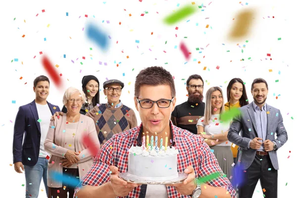 Man celebrating birthday with family and blowing candles on a cake isolated on white background