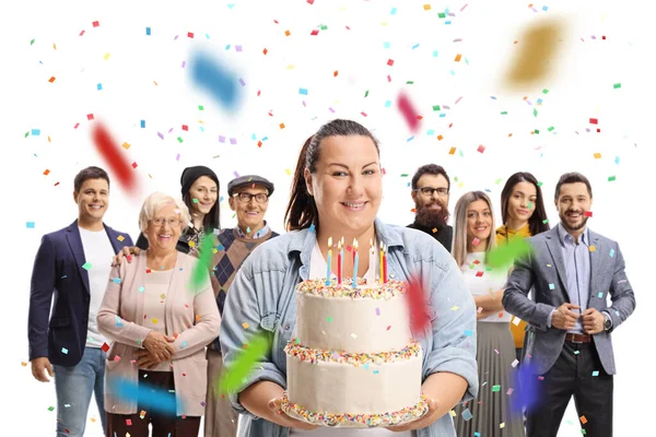 誕生日ケーキを持っている腐敗した若い女性と白い背景に隔離されたお祝いで後ろに立っている人々 — ストック写真