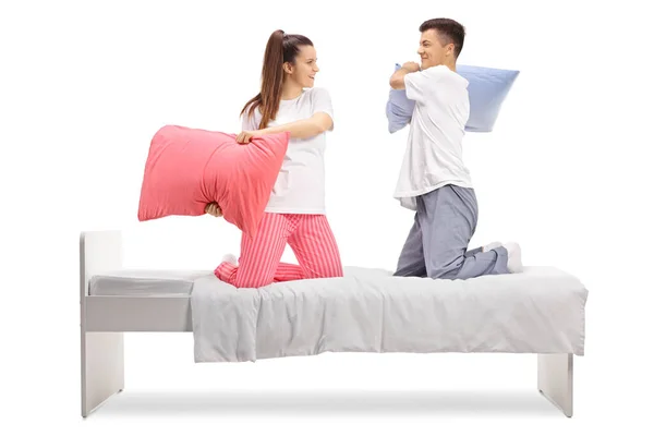 穿着睡衣 枕着枕头 躺在被白色背景隔开的床上打斗的男女青年 — 图库照片