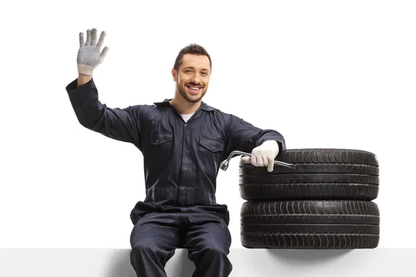Auto Mechanic Sitting Panel Pile Tires Wrench Waving Isolated White — Stock Photo, Image