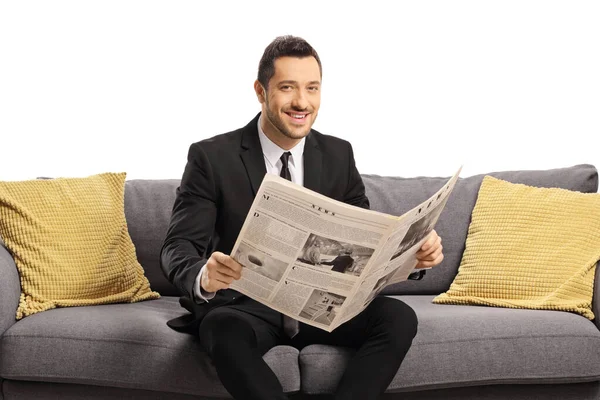 Ung Affärsman Läser Tidning Soffa Och Ler Mot Kameran Isolerad — Stockfoto