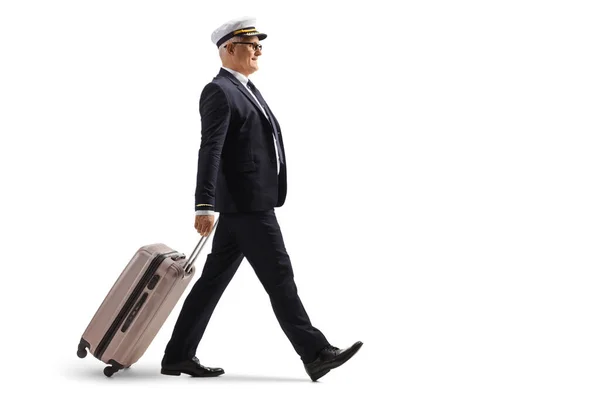 歩行と白い背景に隔離されたスーツケースを引っ張っパイロットの完全な長さプロファイルショット — ストック写真