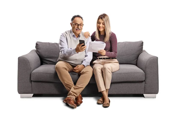 父と娘はソファに座って 白い背景に隔離されたスマートフォンと紙の文書を見て — ストック写真