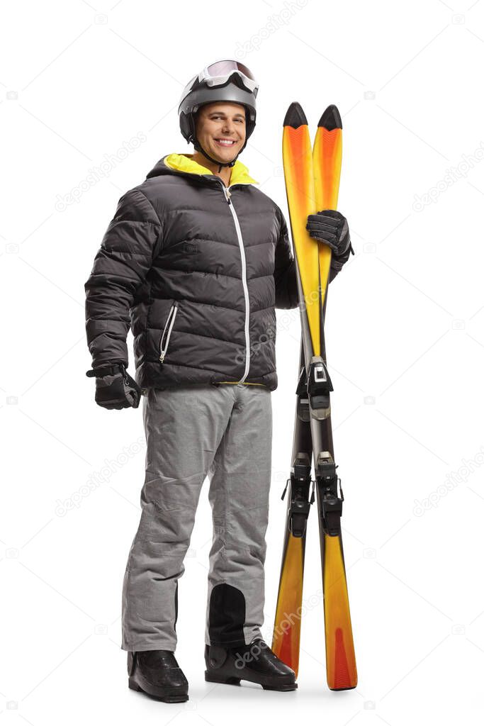 Full length portrait of a young man holding a pair of skis isolated on white background