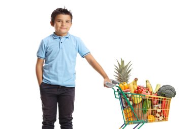 Beyaz arka planda küçük bir alışveriş arabasıyla poz veren çocuk