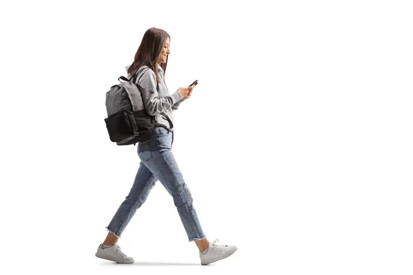 白い背景に隔離された携帯電話で歩く女性学生の完全な長さのプロフィールショット — ストック写真