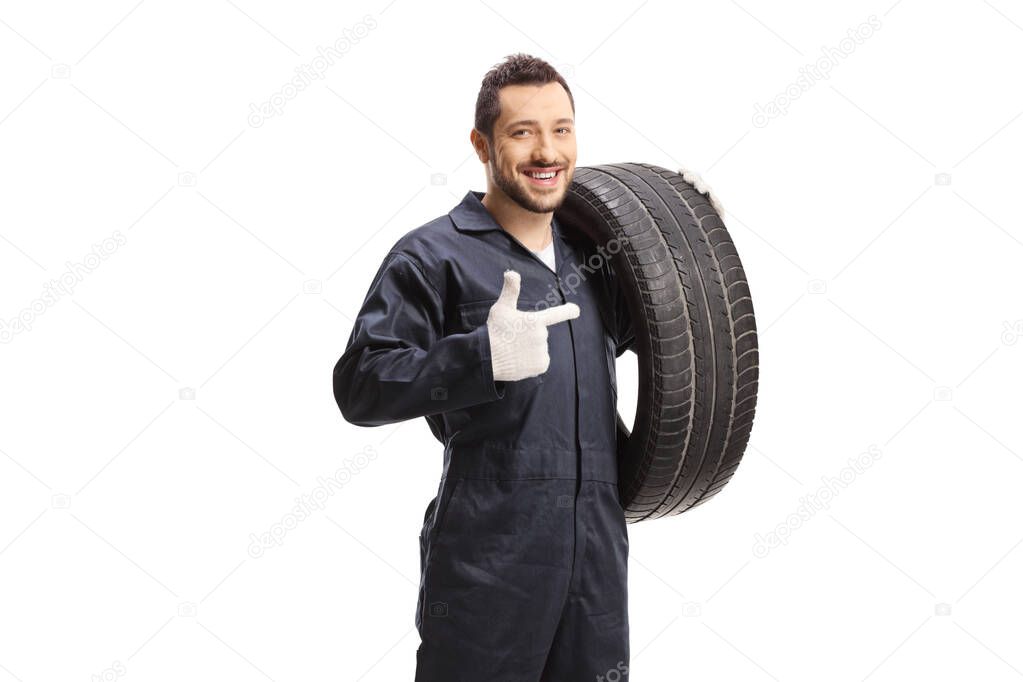 Auto mechanic holding a of car tire and pointing isolated on white background