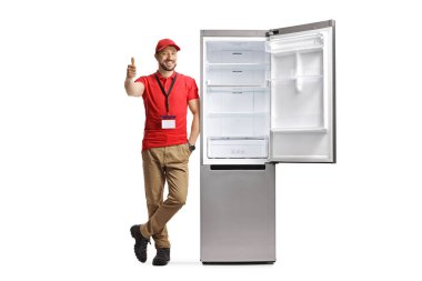 Erkek mağaza asistanı buzdolabına yaslanıyor ve beyaz arka planda izole edilmiş baş parmaklarını gösteriyor.