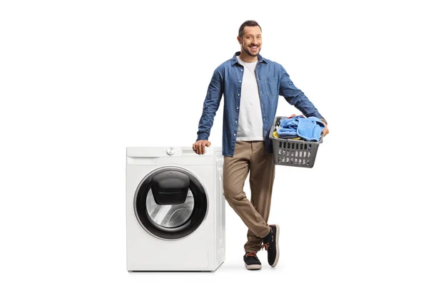 洗濯バスケットと洗濯機を備えたカジュアルな若い男が白い背景に隔離されています — ストック写真