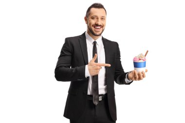 Takım elbiseli ve kravatlı bir adam, beyaz arka planda izole edilmiş bir yeri gösteren bir kağıt bardakta dondurmalı.