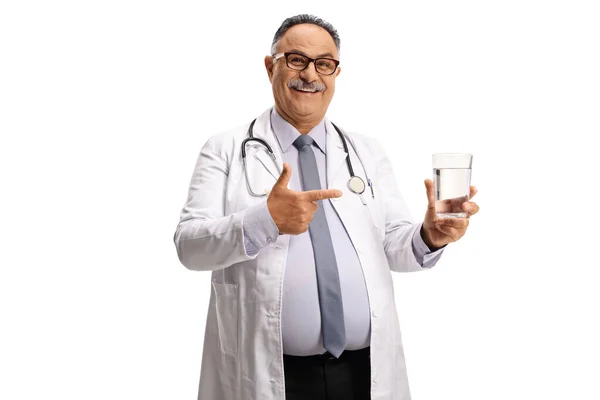 成熟した男性医師は 水のガラスを保持し それを指す白の背景に隔離 — ストック写真