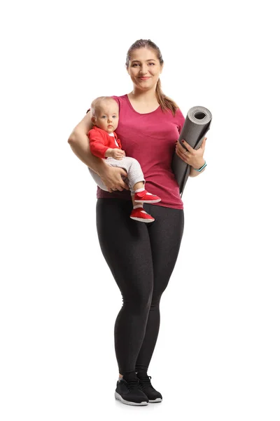 白い背景に孤立した赤ん坊と運動マットを持つ母親の完全な長さの肖像画 — ストック写真