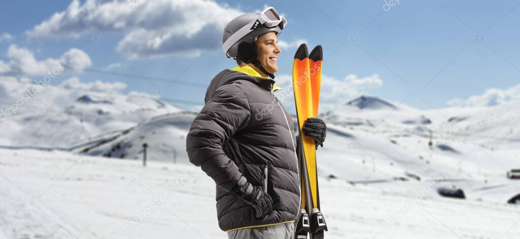 Profile shot of a man holding skis on a snowy mountain 