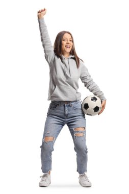 Kot pantolon ve kapüşonlu kadın futbol fanatiği beyaz arka planda izole edilmiş bir top tutuyor.