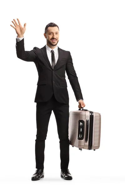 白い背景に隔離されたカメラで手を振ってスーツケースを持つ乗客の完全な長さの肖像画 — ストック写真