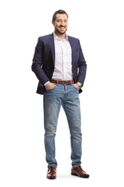 Full length portrait of a man in jeans and suit posing with hands in pockets and smiling isolated on white background