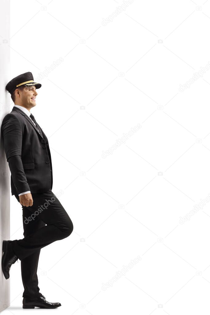 Full length profile shot of a chauffeur in a uniform leaning on a wall isolated on white background