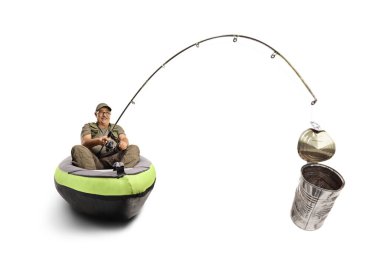 Fisherman sitting in a canoe and catching a tin can with a fishing rod isolated on white background
