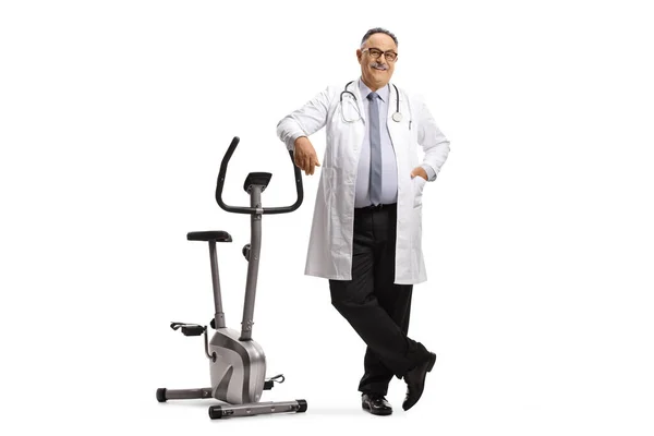 Smiling Mature Doctor Standing Leaning Exercise Bike Isolated White Background — Stock Photo, Image