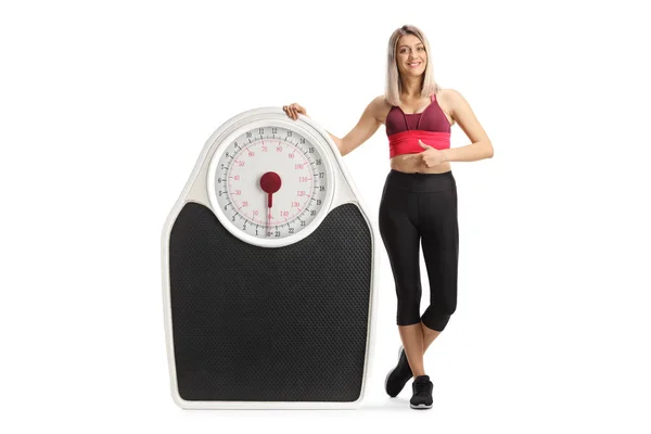 Full Length Portrait Sporty Woman Leaning Big Weight Scale Pointing — Stock Photo, Image