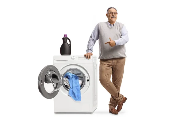 Volwassen Man Leunend Een Wasmachine Met Een Fles Wasgel Wijzend — Stockfoto