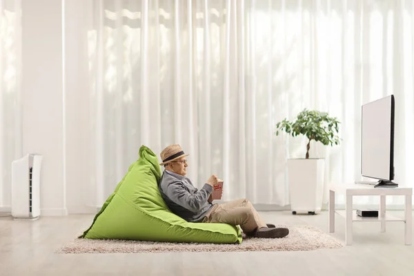 Oudere Man Zittend Een Zitzak Stoel Kijkend Popcorn Etend Een — Stockfoto