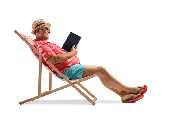 成熟的男性游客阅读一本书 坐在一张白色背景的小椅子上 — 图库照片