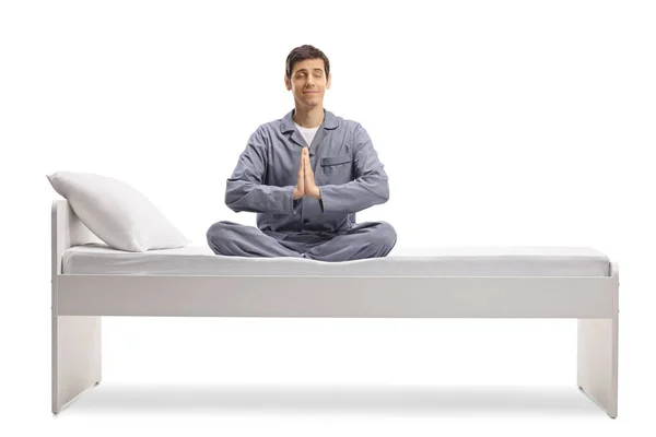 Mladý Muž Nosí Pyžamo Medituje Posteli Izolované Bílém Pozadí — Stock fotografie