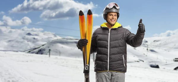 Junger Mann Hält Ein Paar Skier Und Gestikuliert Mit Dem — Stockfoto