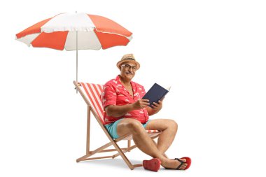 Elinde kitapla bir sandalyede oturan ve beyaz arka planda izole edilmiş kameraya bakan olgun bir adam.