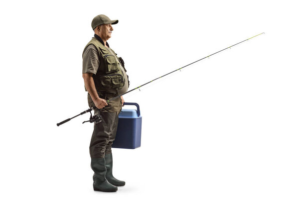 Full length profile shot of a fisherman holding a fishing rod and a portable fridge isolated on white background