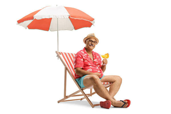 Mature male tourist sitting in a chair with a cocktail under umbrella isolated on white background