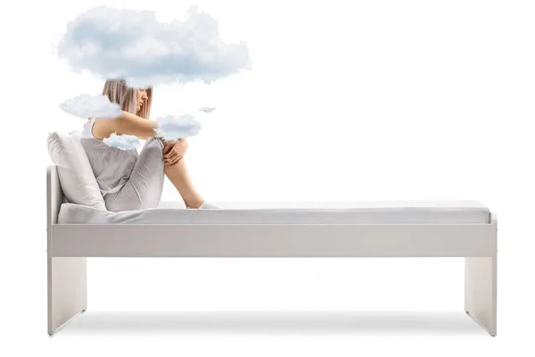 若いです女性でパジャマでベッドの上に座って雲と彼女の頭の周りに隔離された白い背景 — ストック写真