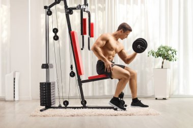 Spor makinesinde halterle egzersiz yapan vücut geliştirici. 