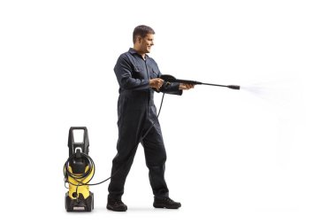 Full length profile shot of a man in a uniform spraying with a pressure washer machine isolated on white background clipart