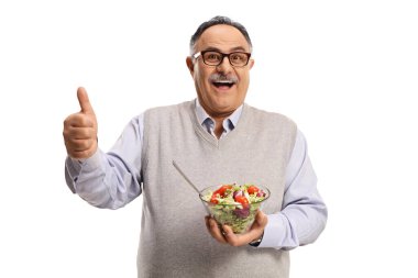 Cheerful mature man holding a healthy fresh salad in a bowl and showing thumbs up isolated on white background