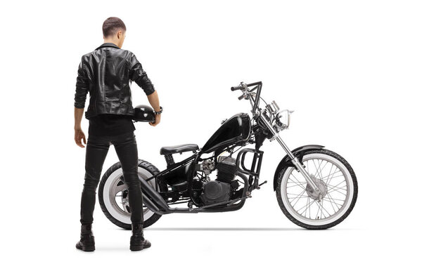 Rear view of a biker in a leather jacket with a chopper holding a helmet isolated on white background