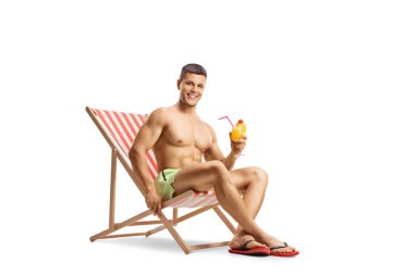 Yüzme şortlu zinde bir adam plaj sandalyesinde oturuyor ve beyaz arka planda izole edilmiş bir kokteyl tutuyor.