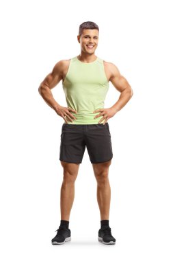 Spor kıyafetli genç adam beyaz arka planda izole edilmiş kameraya gülümsüyor.