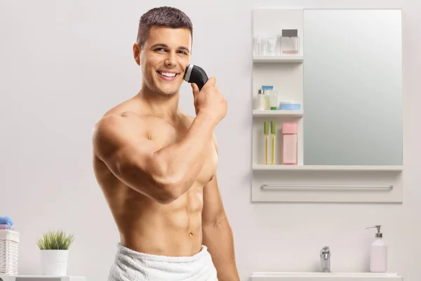 在浴室里用毛巾裹着无袖帅哥用剃须刀 — 图库照片