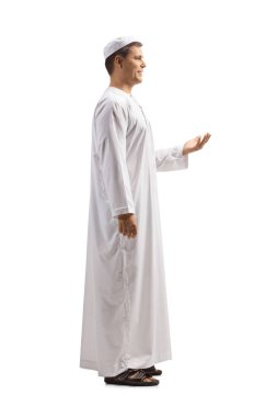 Beyaz etnik giyimli, elleri beyaz arka planda, el kol hareketleriyle hareket eden genç bir adamın tam boy profil çekimi.