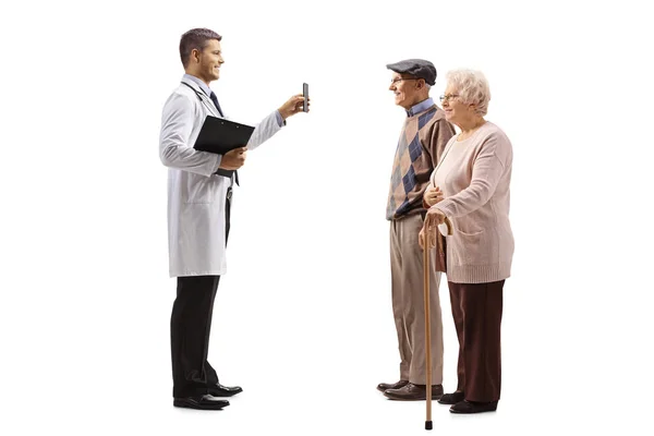 Jovem Médico Mostrando Telefone Celular Para Pacientes Idosos Isolados Fundo — Fotografia de Stock