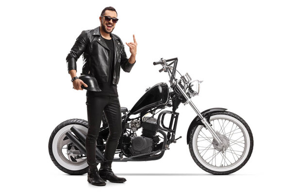 Cool biker with a chopper holding helmet and gesturing rock and roll sign isolated on white background
