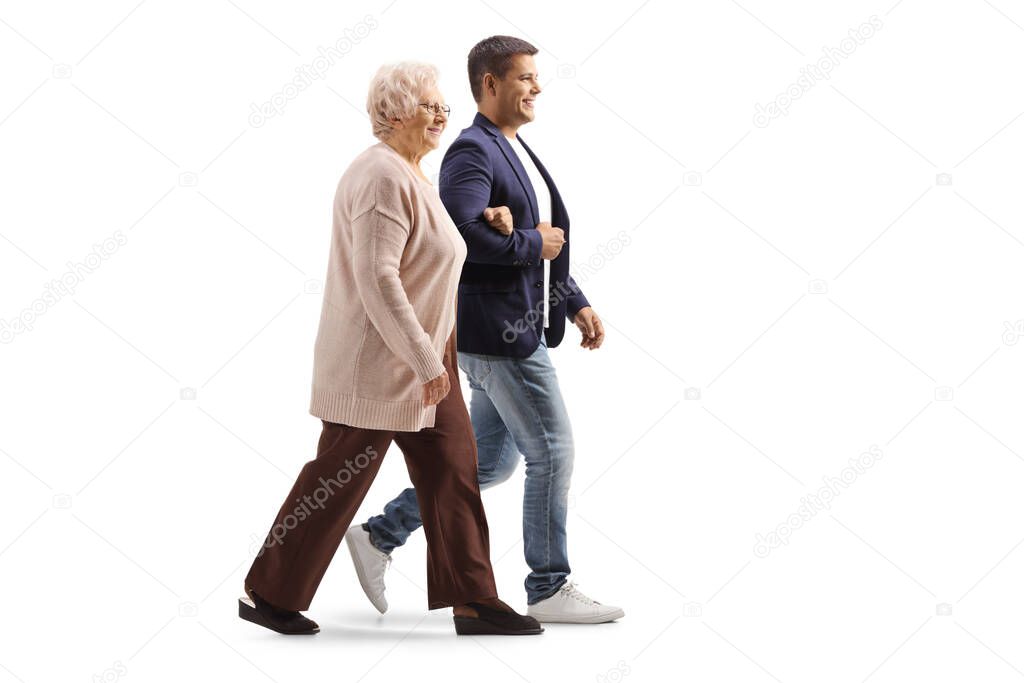 Full length profile shot of a young man walking with an elderly woman isolated on white background