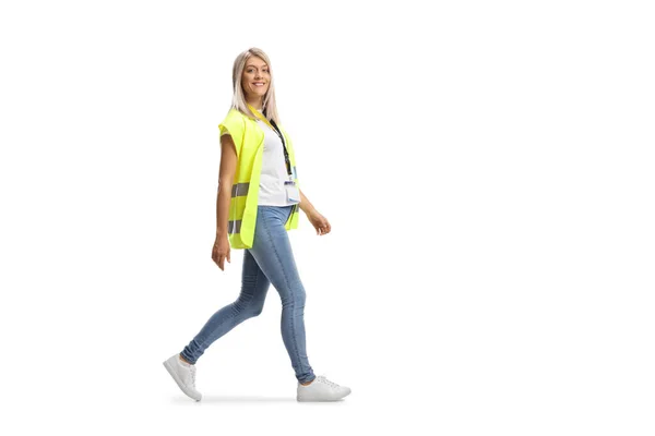 安全ベストを身に着けている若い女性コミュニティ労働者の完全な長さのプロフィールショットと白の背景に隔離された歩行 — ストック写真