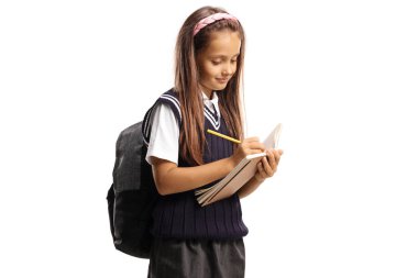 Liseli kız beyaz arka planda izole edilmiş bir defterde duruyor ve yazıyor.