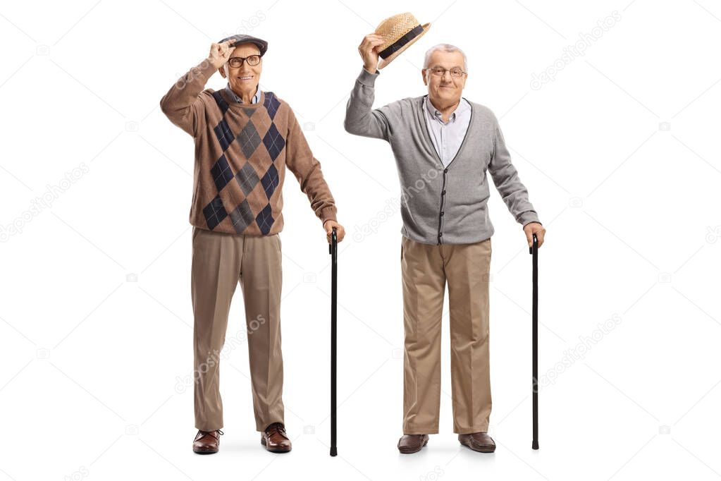 Two gentlemen with walking canes greeting with their hats isolated on white background