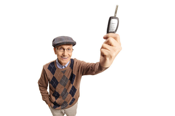 Пожилой счастливый мужчина показывает ключ от машины перед камерой на белом фоне